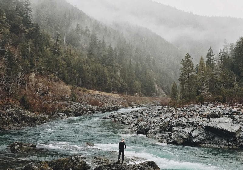 A lone figure beside a rushing mountain river