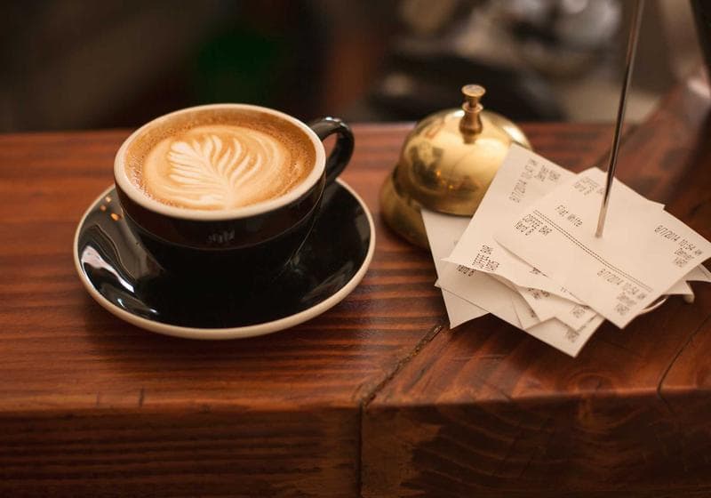 A latte and receipts on a wooden counter